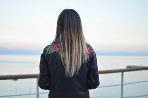 Woman with long, poker-straight hair looking out across the sea